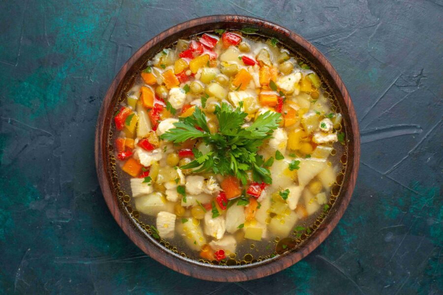 top view delicious vegetable soup with sliced vegetables greens dark blue surface soup vegetable food meal hot food dinner sauce e1737768937147