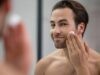 half naked man standing near mirror applying shaving foam his face