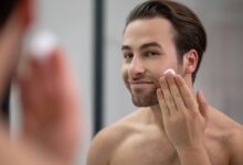 half naked man standing near mirror applying shaving foam his face