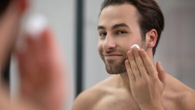half naked man standing near mirror applying shaving foam his face