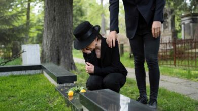 mourning woman cemetery being consoled by man e1738501810607